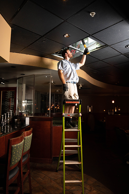 restaurant ac inspection technician on ladder