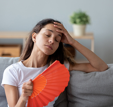 woman faning herself in stuffy hot living room